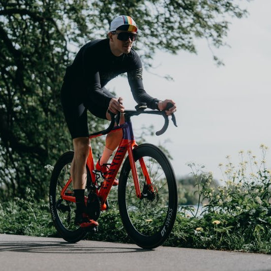 Zwei Rennradfahrer auf der Straße, von vorn aufgenommen – beide in Fahrposition.