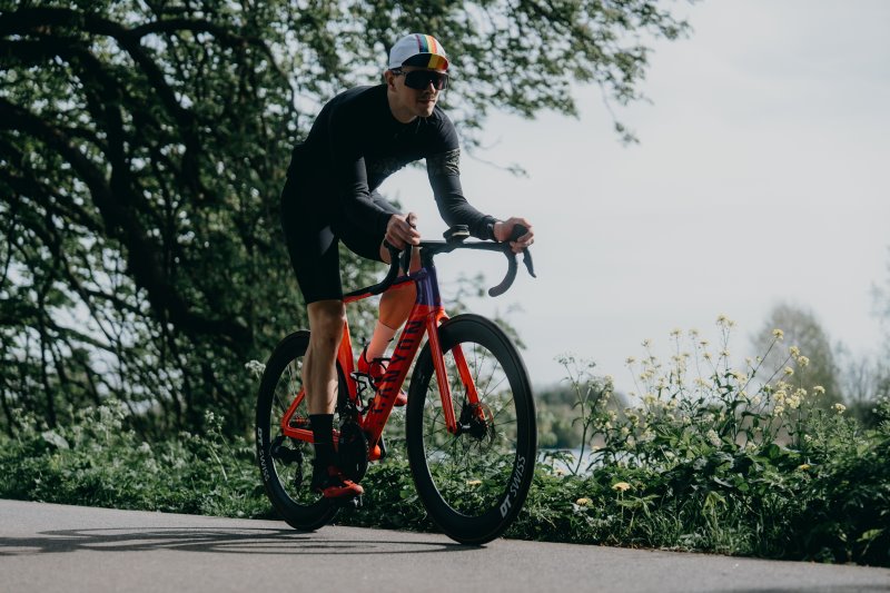 Zwei Rennradfahrer auf der Straße, von vorn aufgenommen – beide in Fahrposition.