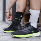 Professional cycling socks for road biking | Statement Socken | Eine schwarze und eine weiße, verbunden durch einen leuchtenden Neonstreifen – als Symbol gegen Rassismus und für Gleichheit.